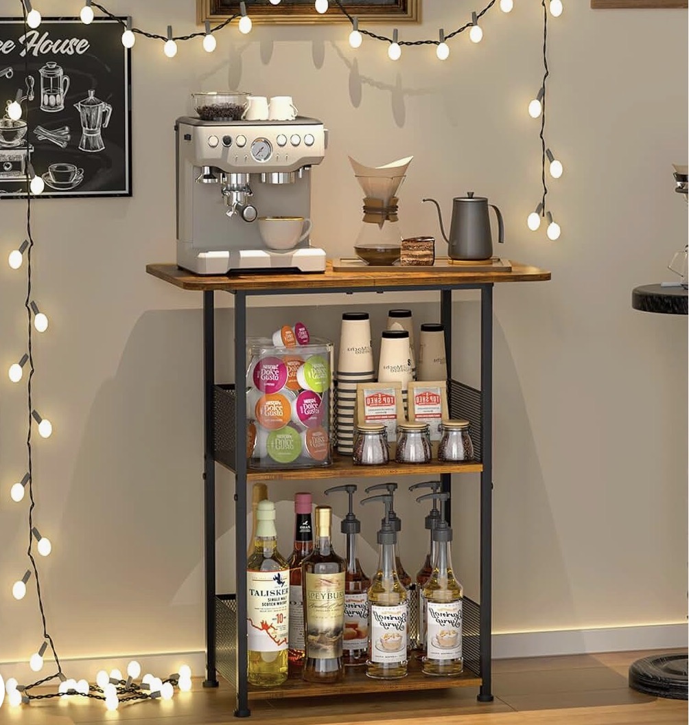 Three-tier farmhouse coffee bar cart in brown wood with a black metal frame holding a coffee maker, cups, and syrup bottles